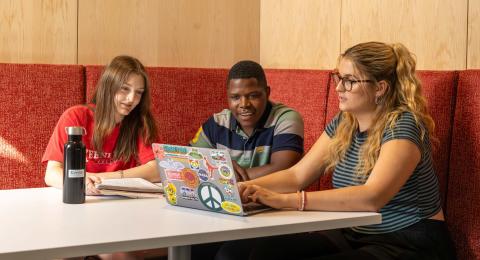Three students working on a laptop