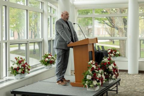 Matt Zabko at podium with red and white flowers